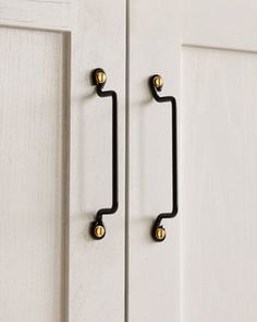 an image of a door handle on the front of a white cabinet with gold knobs