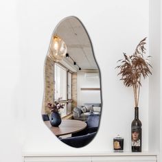 a mirror reflecting a living room with a vase on the table and a couch in the background