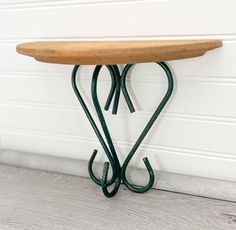 an iron and wood table sitting against a white wall