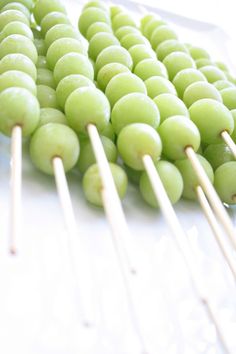 green grapes are on skewers with toothpicks in the foreground and white background