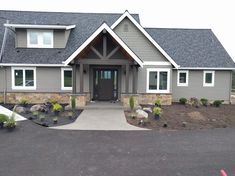 a large gray house with white trim on the front door and windows, along with landscaping