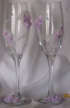 two wine glasses decorated with purple flowers and beaded lace on the bottom one is empty