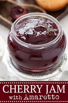 a jar of jam sitting on top of a table next to doughnuts and cherries