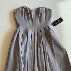 A Perfect Bridesmaid Dress, Or Use For Any Occasion! New With Tags- Purchased In 2016 For A Wedding, But Wore Something Else And It Has Been Sitting In A Closet Ever Since! In Great Condition. Colour Is A Nice Neutral Grey With Some Purple Ish Undertones. A-line Pleated Dress For Wedding Guest, Strapless Pleated Wedding Dresses, Elegant Spring Strapless Dress Lined, Elegant Spring Strapless Lined Dress, Strapless Spring Dress For Formal Occasions, Strapless Dress For Spring Formal, Lined Midi-length Wedding Dress, Elegant Strapless Lined Dress, Strapless Formal Dress For Spring