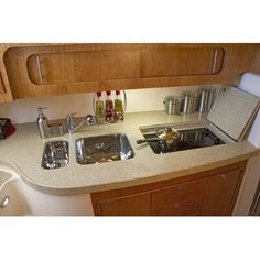 a kitchen counter with two sinks and other items on it's counter top in front of wooden cabinets