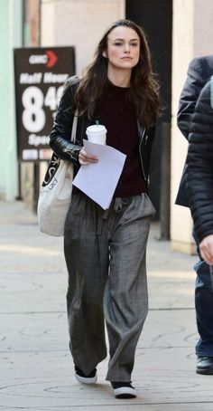 a woman is walking down the street with a coffee cup in her hand and papers in her other hand