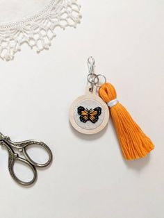 a pair of scissors and a keychain with a butterfly on it sitting next to a lace doily