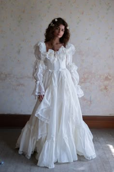 a woman in a white dress standing against a wall