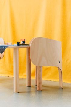 a wooden table and chair sitting in front of a yellow wall with an elephant shaped object on it