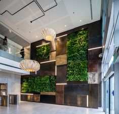 a lobby with plants on the wall and chandeliers hanging from it's ceiling