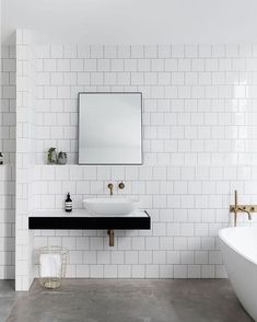 a bathroom with white tiles and black counter tops, along with a large mirror on the wall