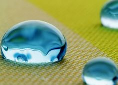 several drops of water sitting on top of a cloth covered tablecloth with yellow and blue colors