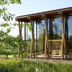 a wooden structure with glass walls in the grass