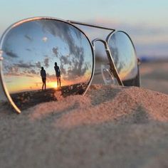 a pair of sunglasses sitting on top of a sandy beach