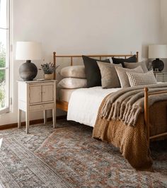 a bed with pillows and blankets on top of it next to a window in a bedroom