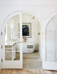 an arched doorway leading to a bathroom with a tub and sink