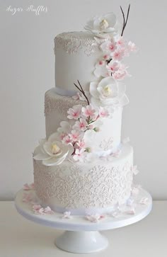 a three tiered white wedding cake with pink flowers