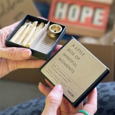 a woman holding a box of candles in her left hand and an open box on the right