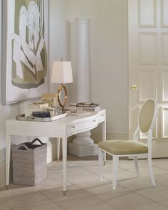 a white desk with a chair next to it and a painting hanging on the wall