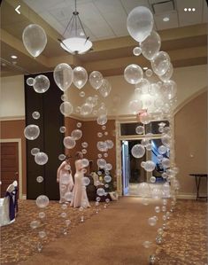 two women are standing in front of bubbles floating from the ceiling at a wedding reception