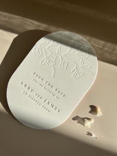 a close up of a white wedding card on a table with shells scattered around it