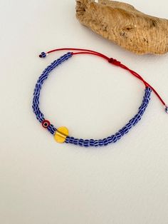 - This minimalist adjustable bracelet features vibrant blue-striped glass seed beads, a striking red cord, and a central red evil eye bead for protection and style. - Handcrafted with a delicate 925 silver charm, gold plated for a luxurious finish, this piece comes from the heart of Istanbul's artisan traditions. - Perfect for layering or wearing alone, this bracelet adds a touch of cultural elegance to your daily wear. A thoughtful gift or a unique accessory for those who appreciate high-qualit Adjustable Blue Friendship Bracelets With Colorful Beads, Handmade Blue Braided Bracelets With Round Beads, Adjustable Blue Braided Bracelet With Colorful Beads, Blue Beaded Braided Bracelets For Jewelry Making, Blue Braided Bracelets With Tiny Beads As Gift, Blue Braided Bracelets With Colorful Beads For Gift, Adjustable Blue Bracelets With Tiny Beads, Blue Evil Eye Bracelet With Sliding Knot As Gift, Blue Evil Eye Bracelet With Sliding Knot For Gift