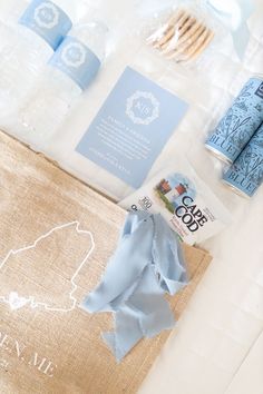 the contents of a travel bag laid out on top of a white tablecloth with blue ribbon