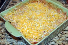 a green casserole dish with cheese and meat in it on a granite countertop