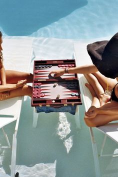 three women sitting around a pool playing backgam game