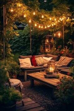 an outdoor seating area with lights strung over the top and pillows on the bottom, surrounded by greenery