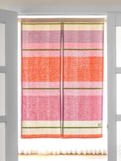 an open window with a pink and green striped curtain