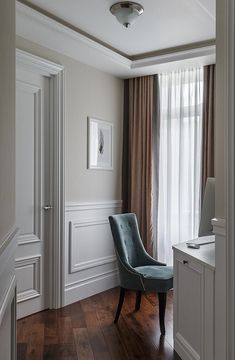 a blue chair sitting on top of a hard wood floor next to a white wall