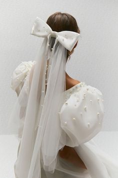 the back of a woman's head wearing a white veil with pearls on it