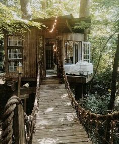 a small wooden cabin in the woods with lights strung from it's roof and door