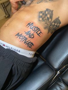 a man with a tattoo on his stomach sitting in a chair holding a cell phone to his ear