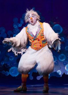 a man dressed as a chicken standing on stage with his arms out in front of him