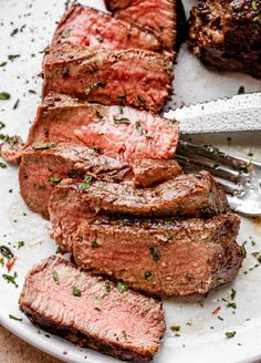 sliced steak on a plate with a fork and knife next to it, ready to be eaten