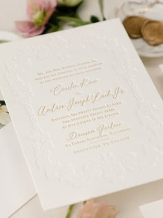 a white wedding card with gold lettering on it