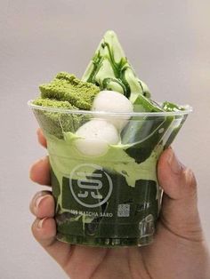 a person holding up a green smoothie with broccoli and eggs in it