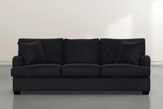 a black couch sitting on top of a gray floor next to a white wall in a living room