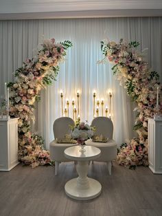 an elegant wedding setup with white chairs and flowers on the wall, candles in the background