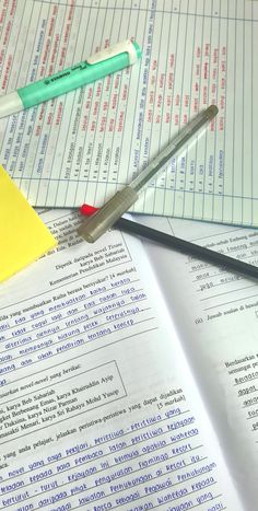 a pair of scissors sitting on top of an open book next to a pen and ruler