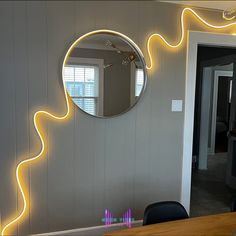 a mirror that is on the side of a wall next to a table and chair