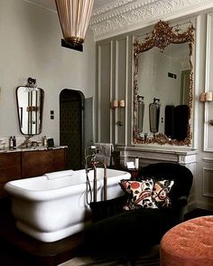 a bathtub and chair in a room with mirrors on the walls