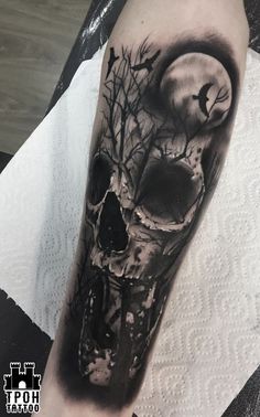 a black and white skull with a full moon behind it on the left upper arm