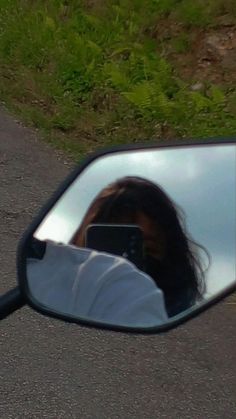 a rear view mirror reflecting a woman's face in the side view mirror on a motorcycle