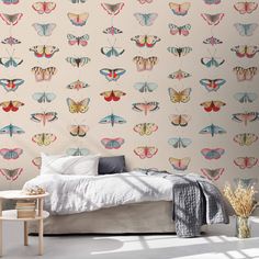 a bed sitting next to a wall covered in butterflies