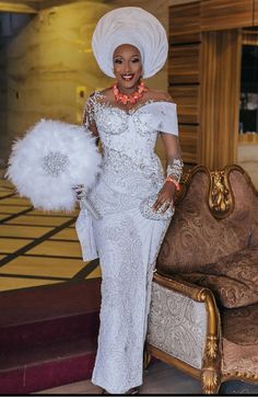 a woman in a white dress and headdress standing next to a couch