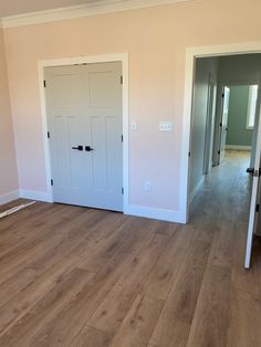 an empty room with white doors and hard wood flooring on the side of the wall