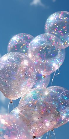 several clear balloons floating in the air with glitter on them and blue sky behind it